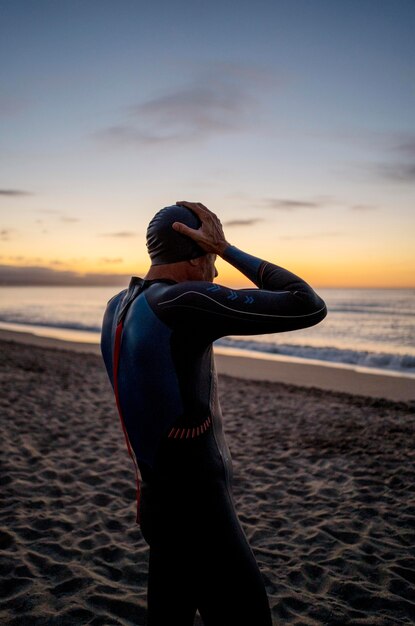 Hombre de tiro medio en la playa al atardecer