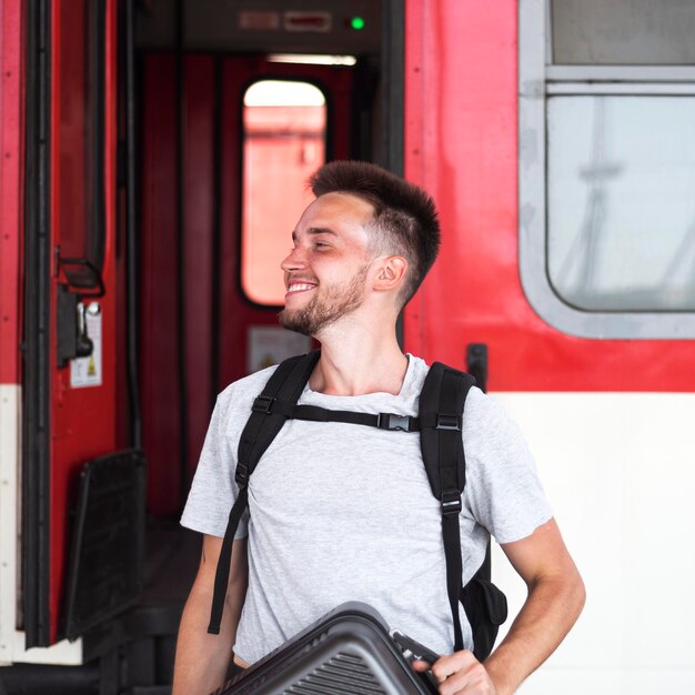 Hombre de tiro medio posando cerca del tren