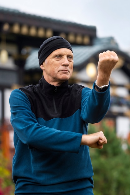 Hombre de tiro medio practicando tai chi al aire libre