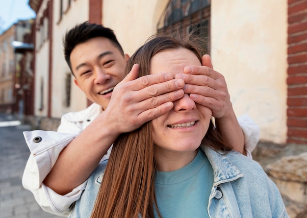 Hombre de tiro medio que cubre los ojos de la mujer