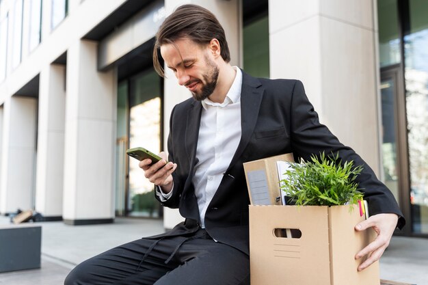 Hombre de tiro medio que renuncia con un teléfono inteligente