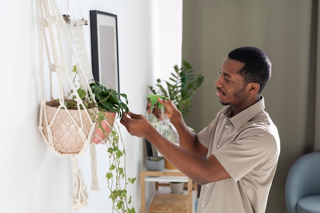 Hombre de tiro medio regando plantas en casa