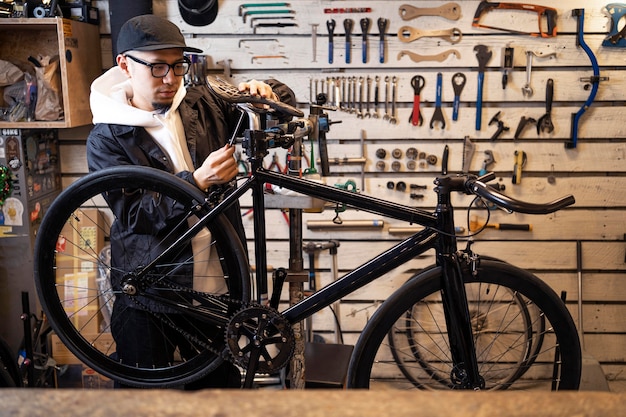 Hombre de tiro medio reparando bicicleta en la tienda