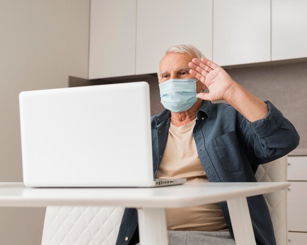 Hombre de tiro medio saludando a la computadora portátil