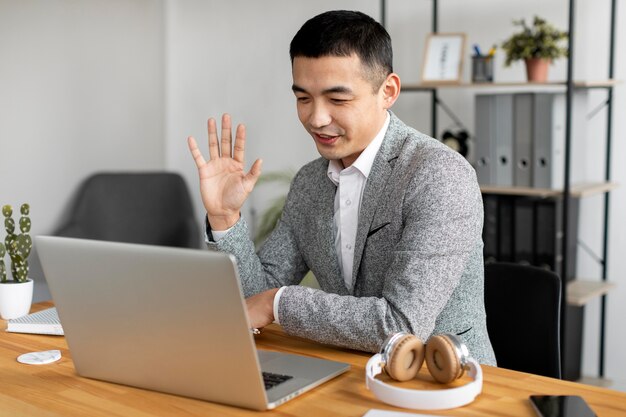 Hombre de tiro medio saludando a la computadora portátil