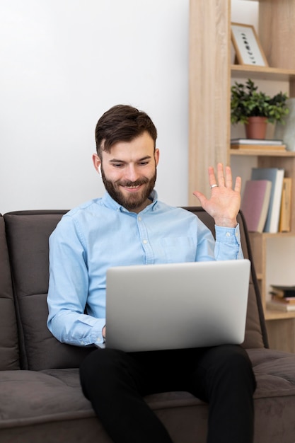 Hombre de tiro medio saludando a la computadora portátil