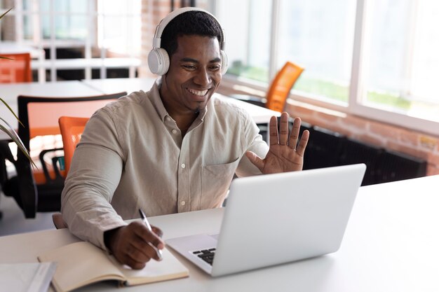 Hombre de tiro medio saludando a la computadora portátil