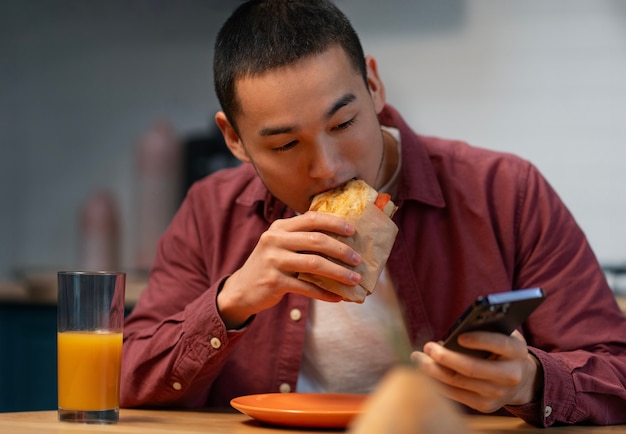 Hombre de tiro medio con sándwich envuelto en papel