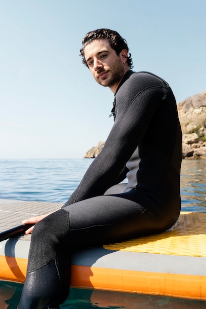 Foto gratuita hombre de tiro medio sentado en la tabla de surf