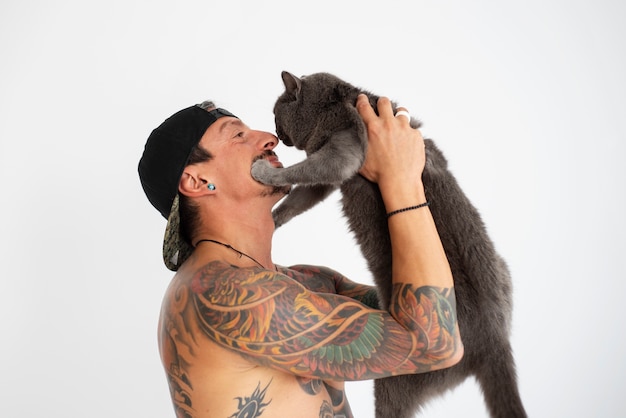 Hombre de tiro medio siendo cariñoso con lindo gato