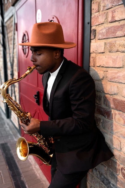 Foto gratuita hombre de tiro medio con sombrero tocando el saxofón