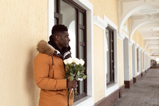 Foto gratuita hombre de tiro medio sosteniendo flores