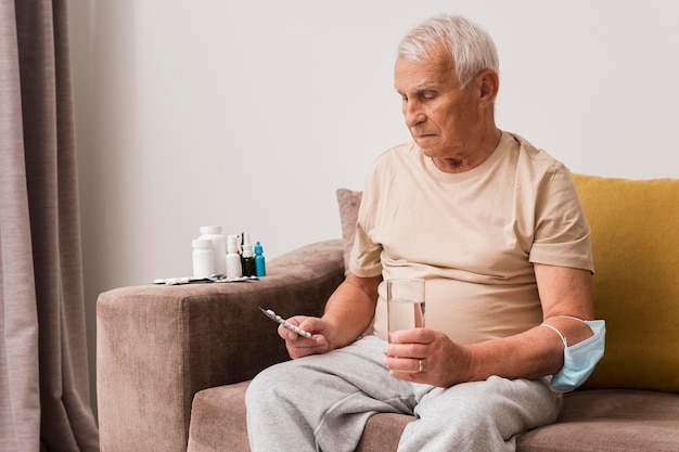 Foto gratuita hombre de tiro medio sosteniendo pastillas y vaso de agua