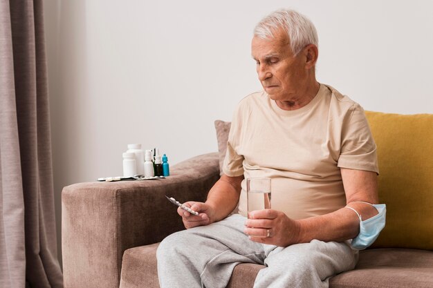 Hombre de tiro medio sosteniendo pastillas y vaso de agua