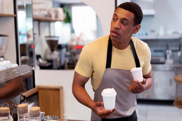 Hombre de tiro medio sosteniendo vasos de papel