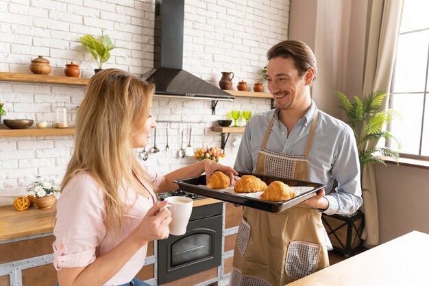 Hombre de tiro medio sujetando la bandeja de croissant