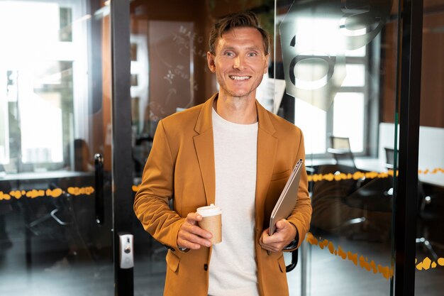 Hombre de tiro medio sujetando un portátil y una taza de café