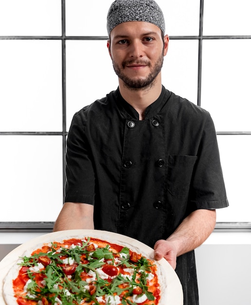 Hombre de tiro medio sujetando la tabla de cortar con pizza