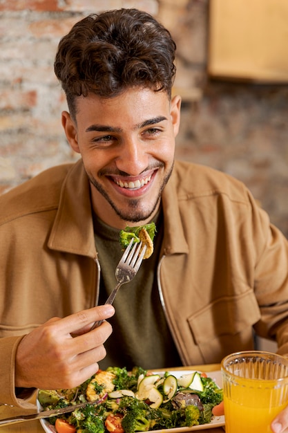 Hombre de tiro medio sujetando un tenedor con comida