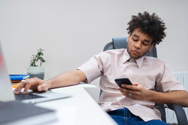 Foto gratuita hombre de tiro medio con teléfono y computadora portátil