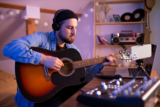 Hombre de tiro medio tocando la guitarra en casa.