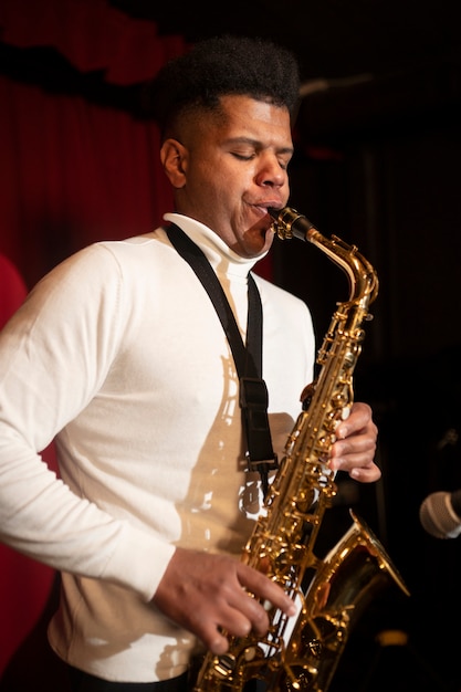 Hombre de tiro medio tocando el saxofón.