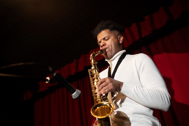 Hombre de tiro medio tocando el saxofón.