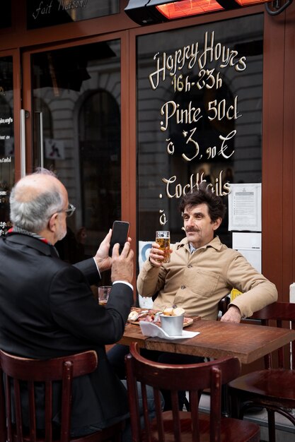 Hombre de tiro medio tomando fotos de un amigo mayor