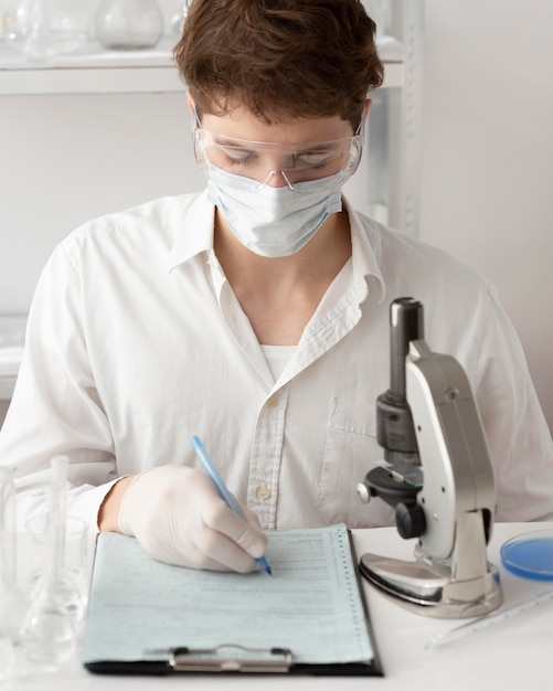 Hombre de tiro medio trabajando con microscopio