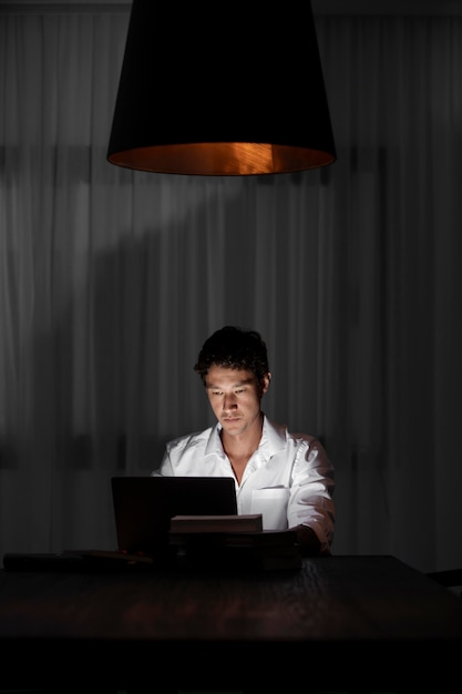 Foto gratuita hombre de tiro medio trabajando por la noche con un portátil