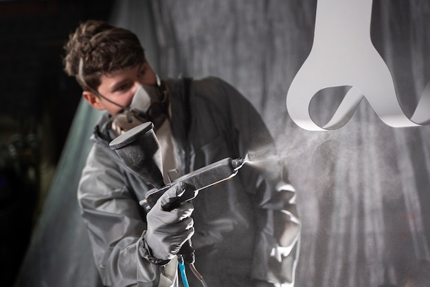 Hombre de tiro medio trabajando con pistola de pintura.