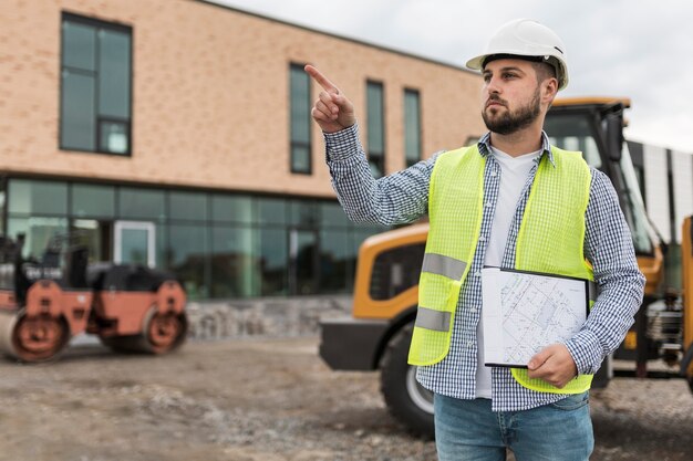 Hombre de tiro medio trabajando en el sitio de construcción