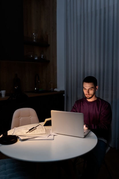 Hombre de tiro medio trabajando tarde en la noche en la computadora portátil