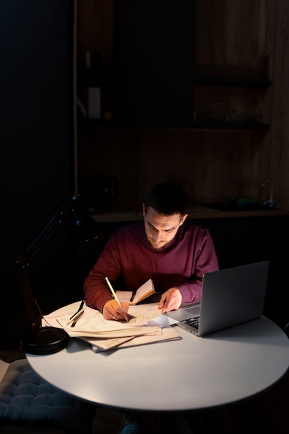 Hombre de tiro medio trabajando tarde en la noche en la computadora portátil