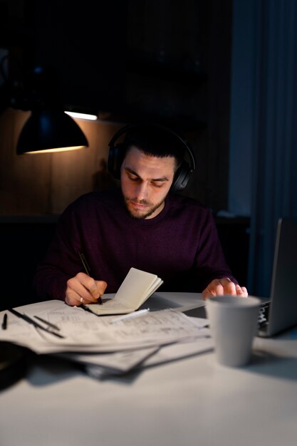 Hombre de tiro medio trabajando tarde en la noche en la computadora portátil