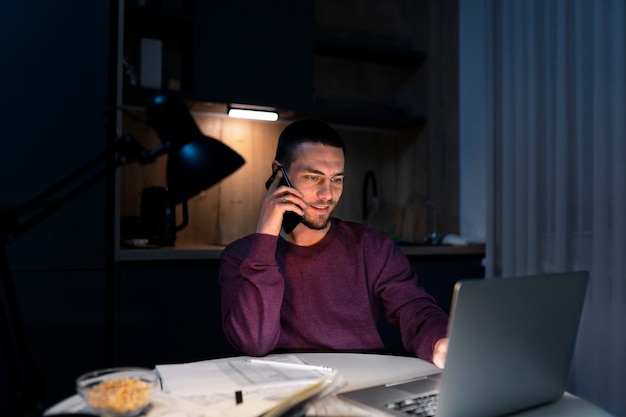Hombre de tiro medio trabajando tarde en la noche en la computadora portátil