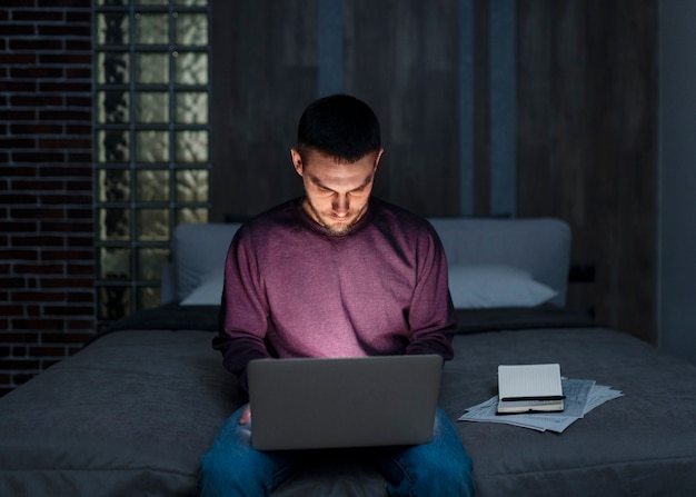 Hombre de tiro medio trabajando tarde en la noche en la computadora portátil