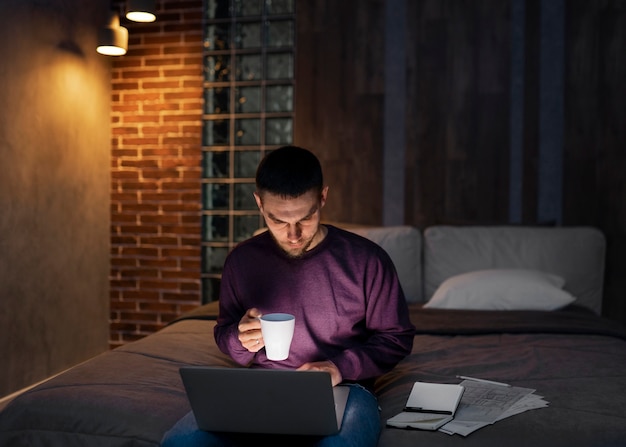 Hombre de tiro medio trabajando tarde en la noche en la computadora portátil