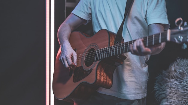 Foto gratuita un hombre toca una guitarra acústica en una habitación oscura. actuación en vivo, concierto acústico, práctica.