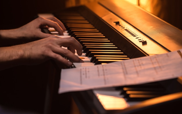 El hombre toca las notas en el piano, primer plano, fondo de color hermoso, el concepto de actividad musical