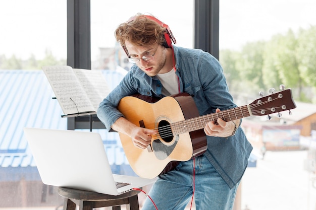 Hombre tocando la guitarra acústica en la casa