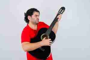 Foto gratuita hombre tocando la guitarra en camiseta roja y mirando enfocado