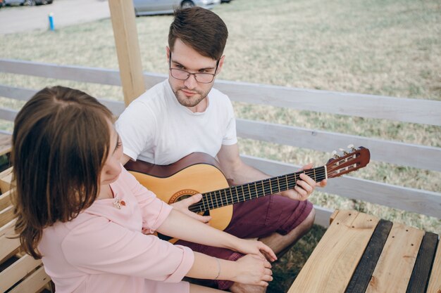 Hombre tocándo la guitarra para una chica joven