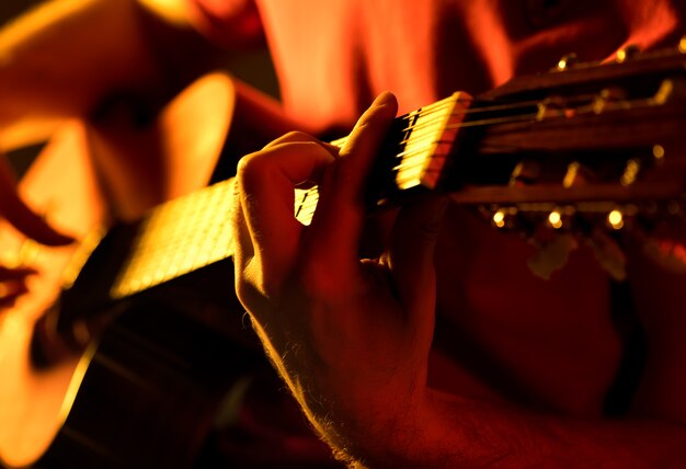 El hombre tocando la guitarra clásica en un escenario concierto musical vista cercana