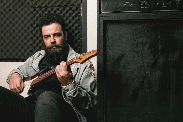 Hombre tocando la guitarra junto al amplificador