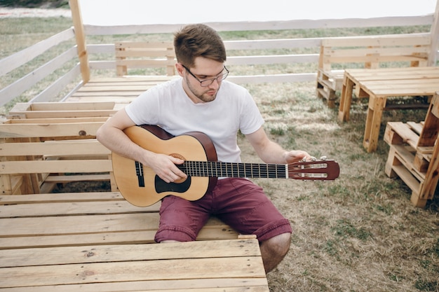 Hombre tocando la guitarra en unas mesas de madera