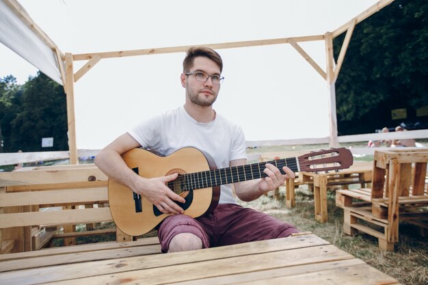 Hombre tocando la guitarra en unas mesas de madera