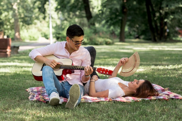 Hombre tocando la guitarra a una mujer