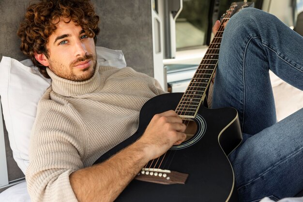 Hombre tocando la guitarra en su coche durante un viaje por carretera