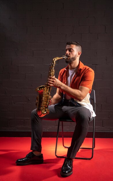 Hombre tocando el saxofón mientras está sentado